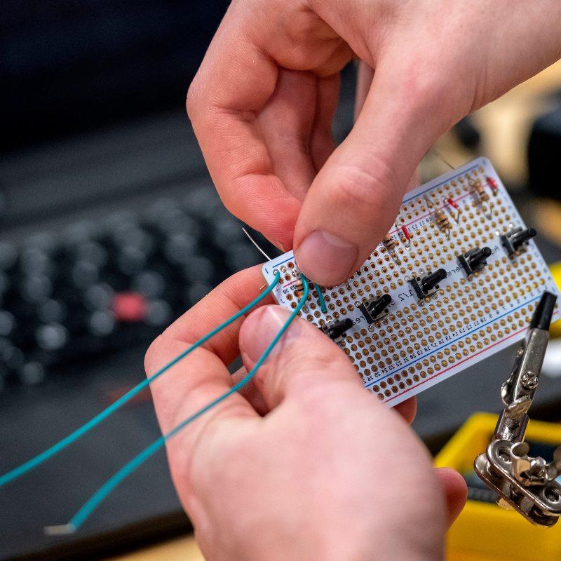 A hand wires electronics.