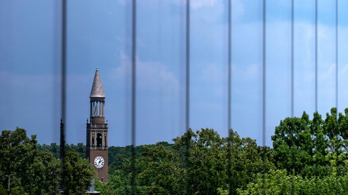 The bell tower is reflected on glass.