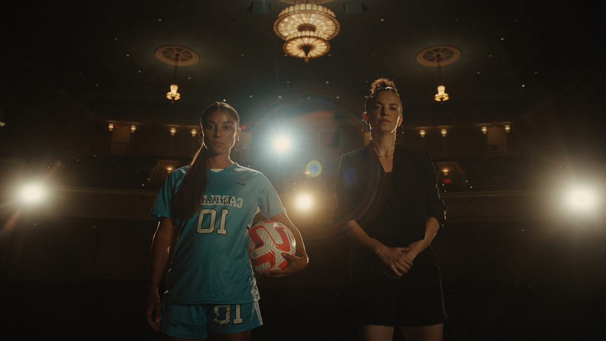 A dancer and a soccer player holding a ball posing for a photo next to each other in a theater.