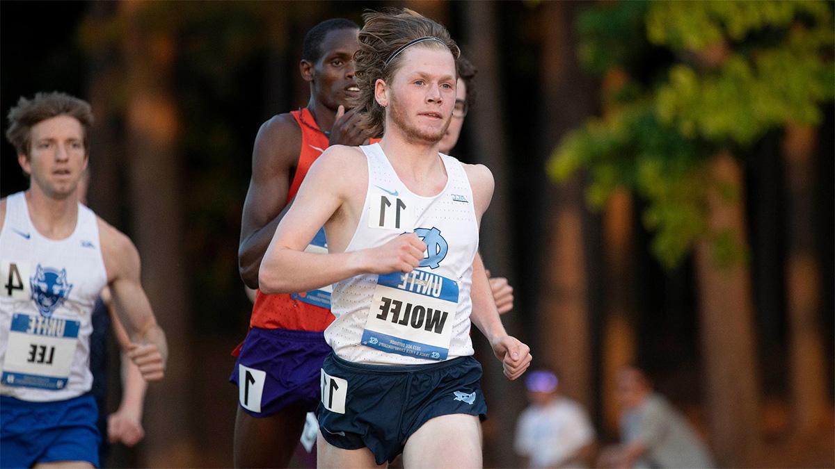 Cross country runner, Parker Wolfe, runs ahead of competition close behind him with a name tag reading 