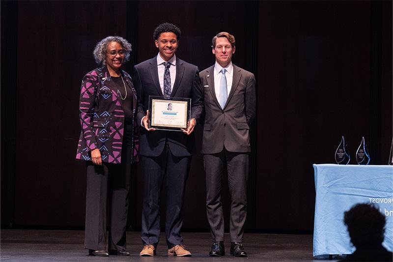 A student, Michael Fair, taking a group photo with two other people on stage, Lee H. 罗伯茨和莉亚·考克斯，在获奖后.