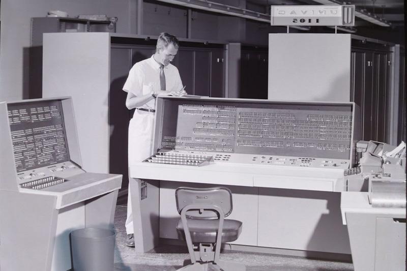 Black-和-white photo of a man in a room-sized computer in the 1950s.