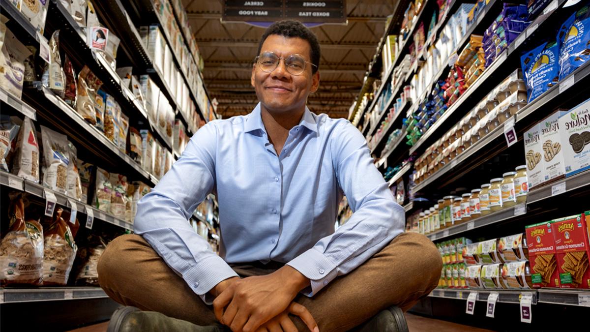 Emile Charles sitting down in the middle of an aisle inside of a grocery store.